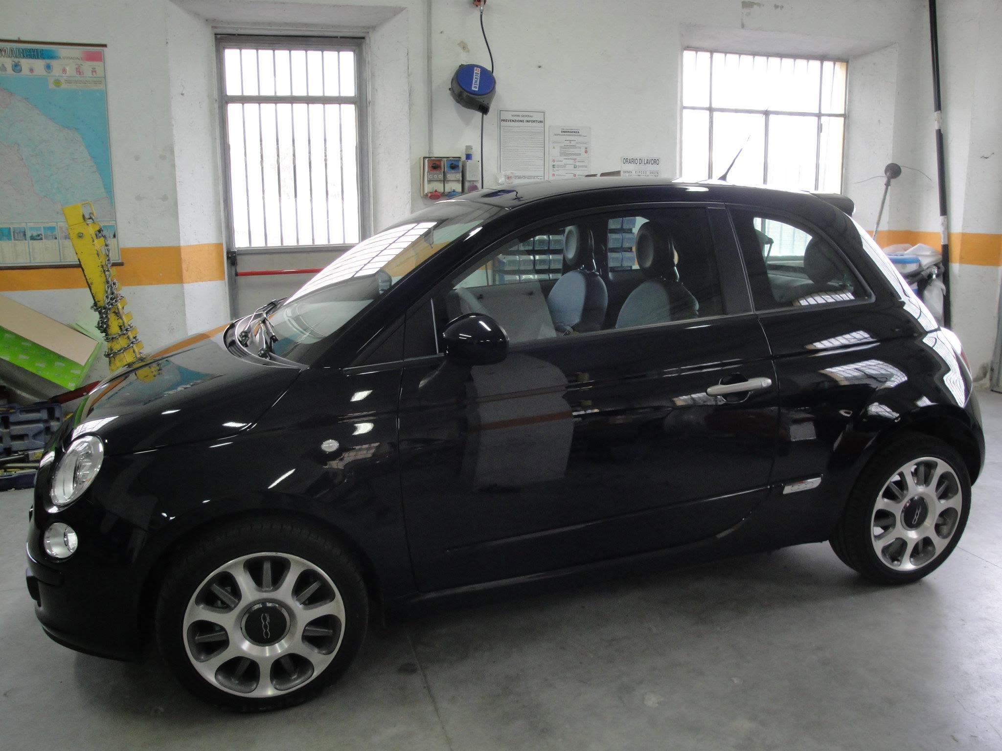Fiat 500 nera vista lateralmente in officina